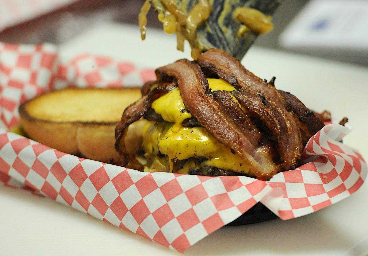 Bacon and onion find their way atop a burger in the kitchen at S.O.B. Burgers in Bradenton.