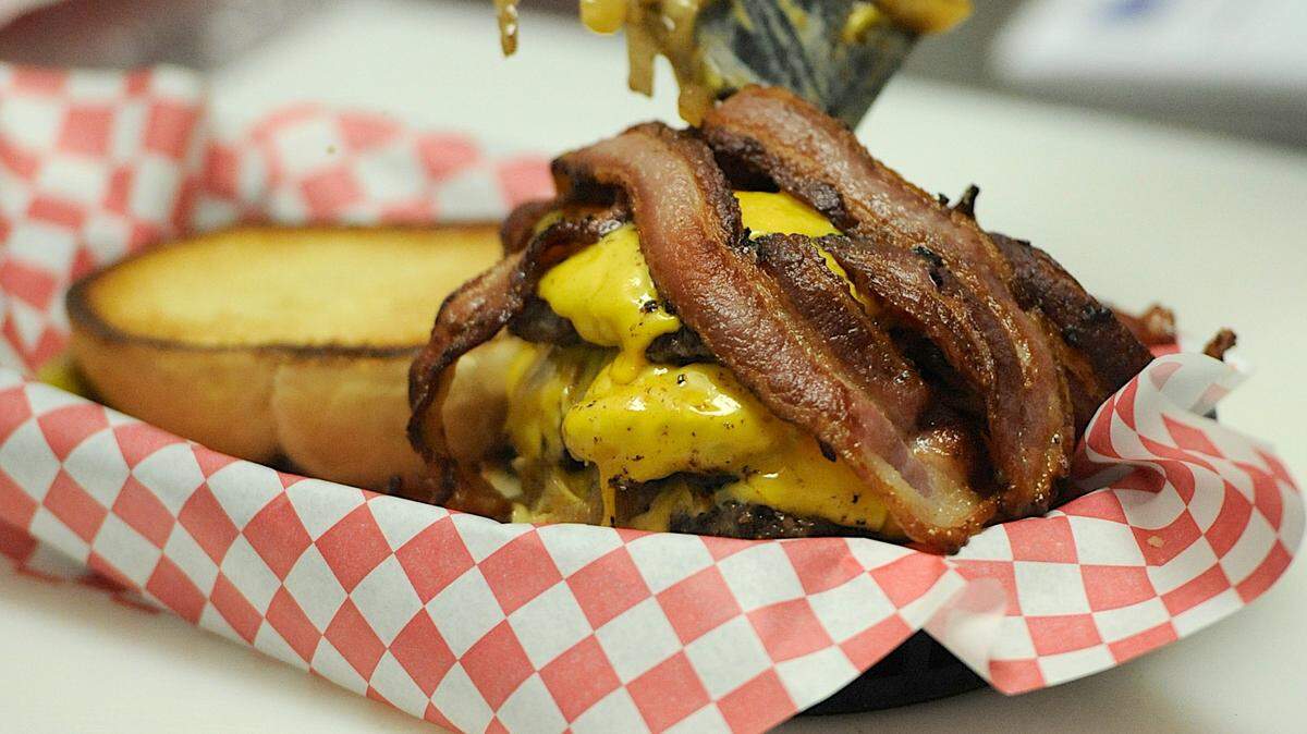 Bacon and onion find their way atop a burger in the kitchen at S.O.B. Burgers in Bradenton.