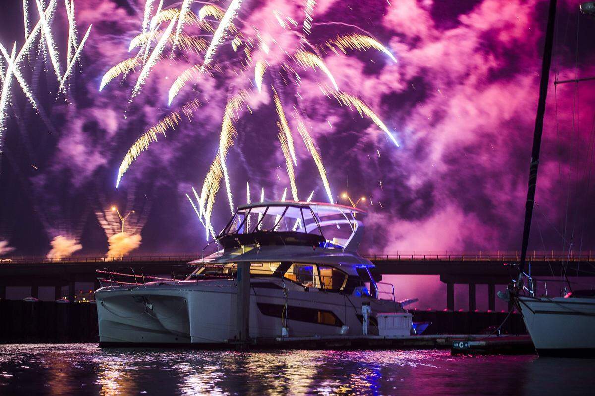 Fireworks explode in the distance behind a boat floating in Twin Dolphin Marina after the third annual Bradenton Area River Regatta in 2017.