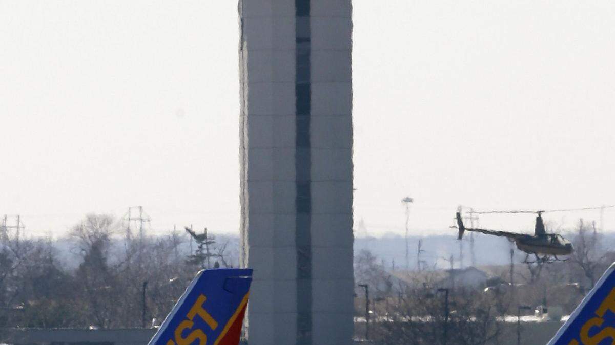 A helicopter flies past the air traffic control tower at Midway International Airport in Chicago. In the coming decades, number of air travelers is expected to approach 7 billion, but there won't be enough controllers to help those 44,000 planes take off and land safely. ASSOCIATED PRESS FILE