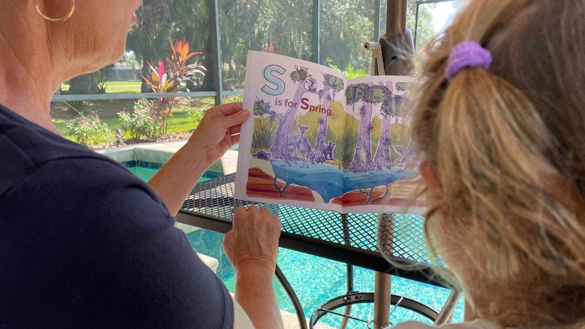 Jodi Carroll reads “Old Manatee A to Z” to her granddaughter, Lillian Kalousek of Lake Forest, Ill. Realize Bradenton recently published the childrens book which is focused on the rich history of East Bradenton.