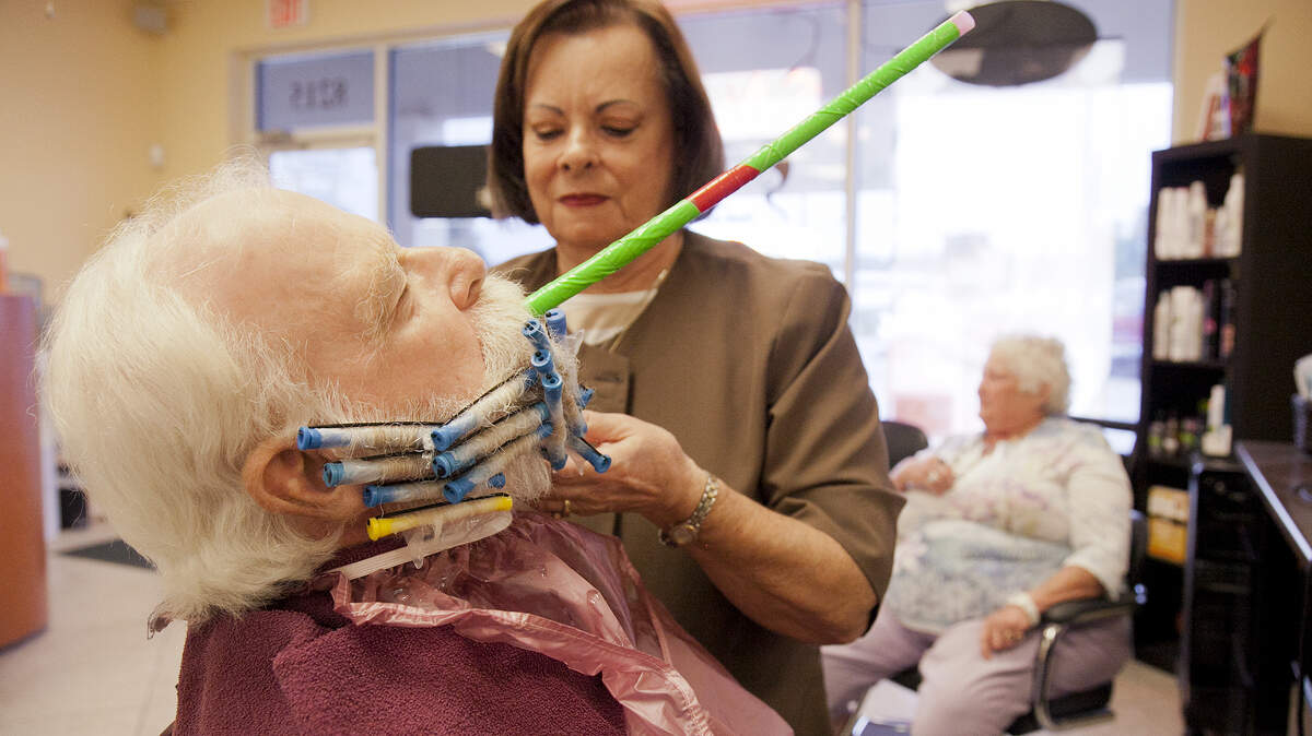 Due to the smell of the chemicals needed to give his beard a curly permanent, John O'Connor breathes through a tube while the curls set. MATT M. JOHNSON/Bradenton Herald