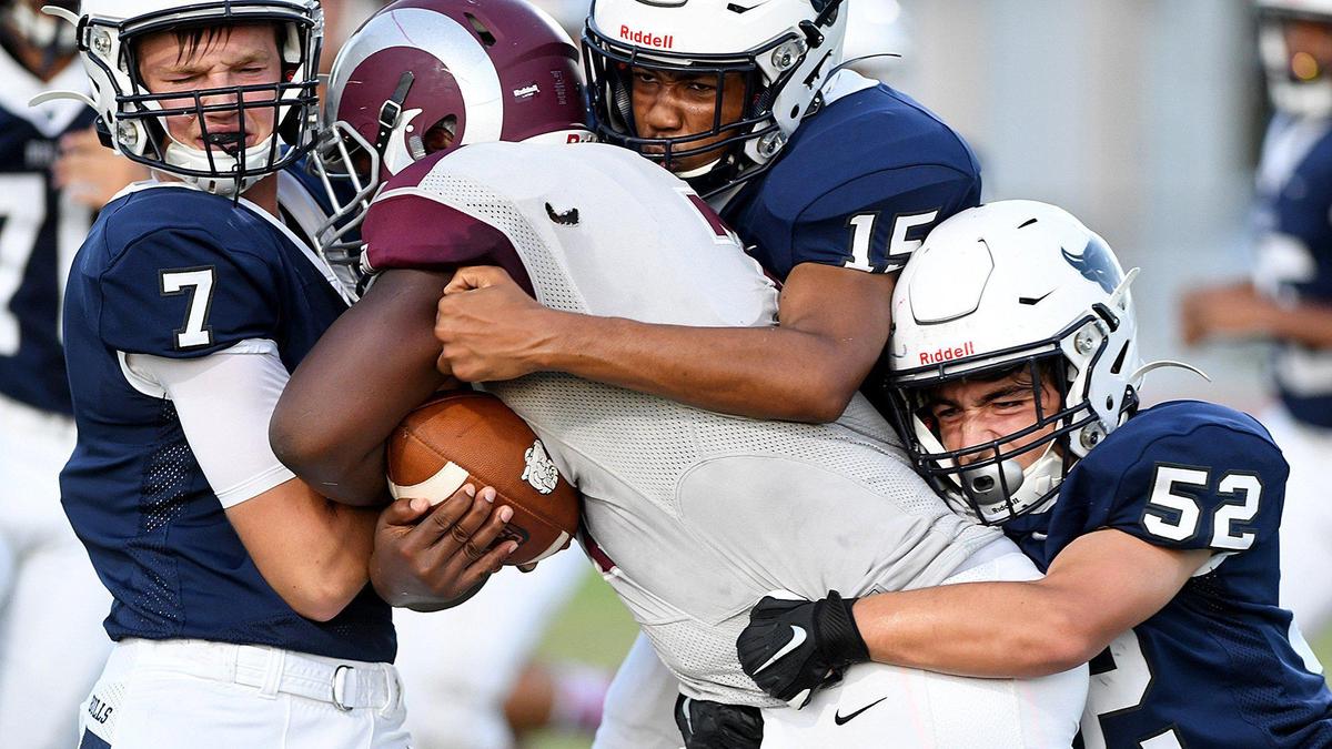 Defenders Mikeal Steele, David Jackson and Tanner Cloud take on a Sarasota Riverview player during last week’s game at Parrish Community High.