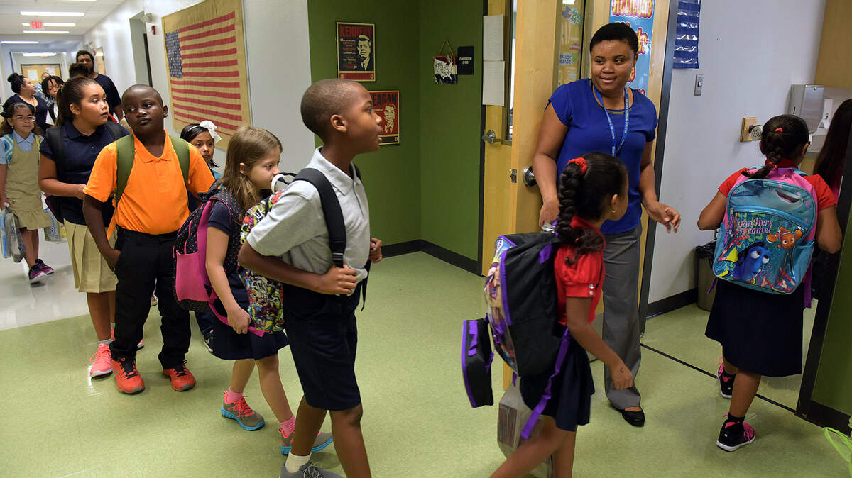 Third-grade teacher Ermite Constant welcomes students into their classroom at Rogers Garden-Bullock Elementary School on the first day of school in 2016.