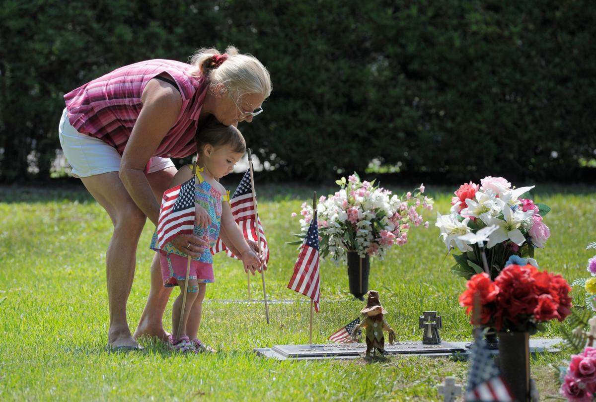 Jean Morone helps her granddaughter Vada Morone place a flag at the gravesite of Vada’s great-grandfather, U.S. Army Veteran and Korean War Veteran Ernest L. Morone, during the “Preparing for Memorial Day” service at Manasota Memorial Park in East Bradenton on Saturday, May 24, 2014.