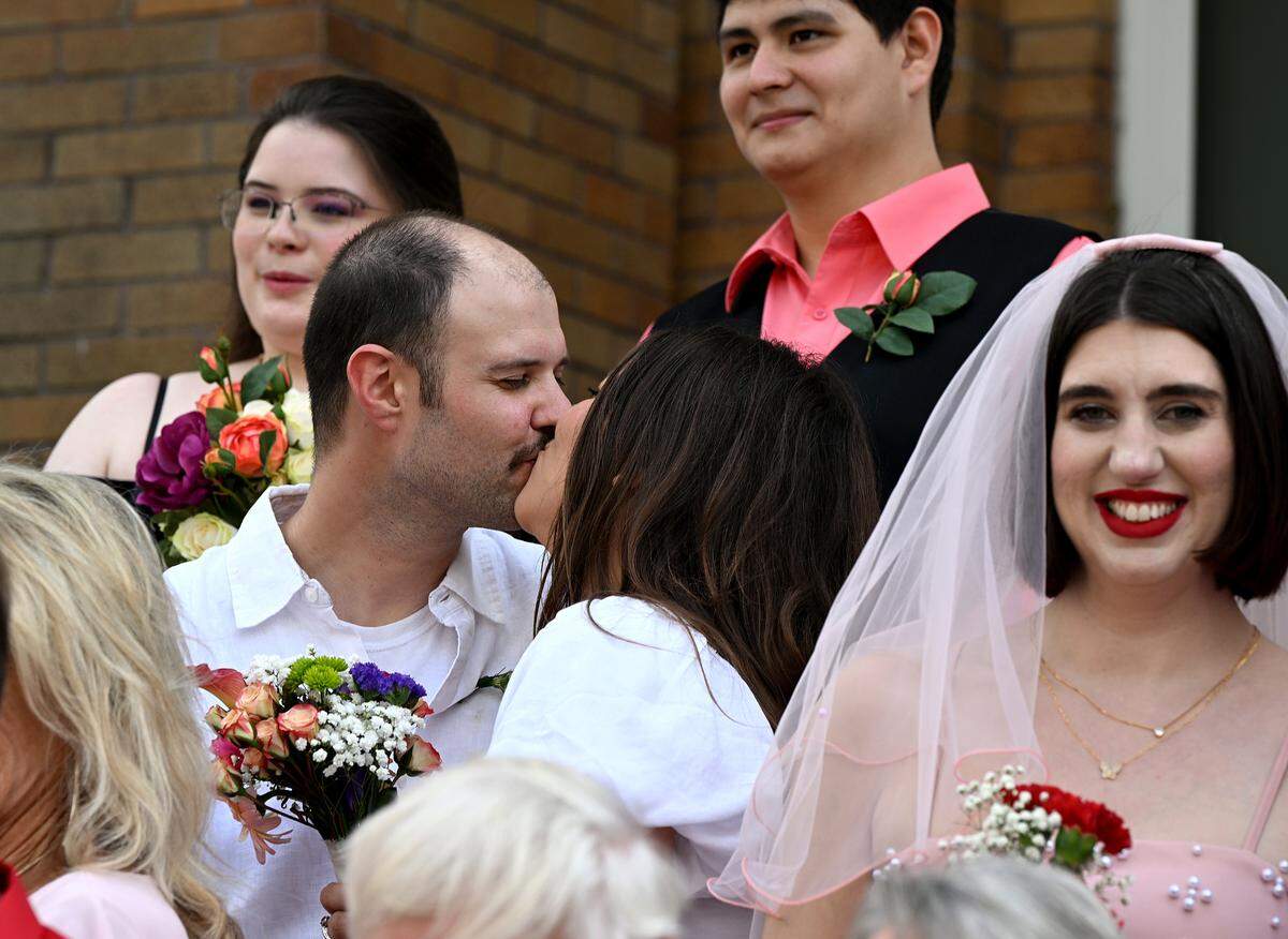 Michael Barber and Jacquelyn Hannan kiss during a group photo.