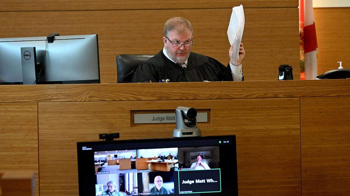 Judge Matt Whyte holds the transcripts up for the entire first day of the trial while the defense team for Ashley Benefield, a Lakewood Ranch woman convicted of manslaughter in the killing of her husband, appeared in a Manatee County courtroom in downtown Bradenton Monday for a hearing over whether to allow jurors to be interviewed after allegations of misconduct on Sept. 16, 2024.
