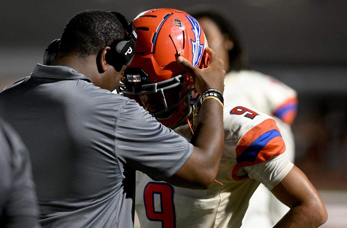 Head coach Brett Timmons talks with Evan Bennett during Friday’s game against Riverview High in Sarasota on August 25, 2023.