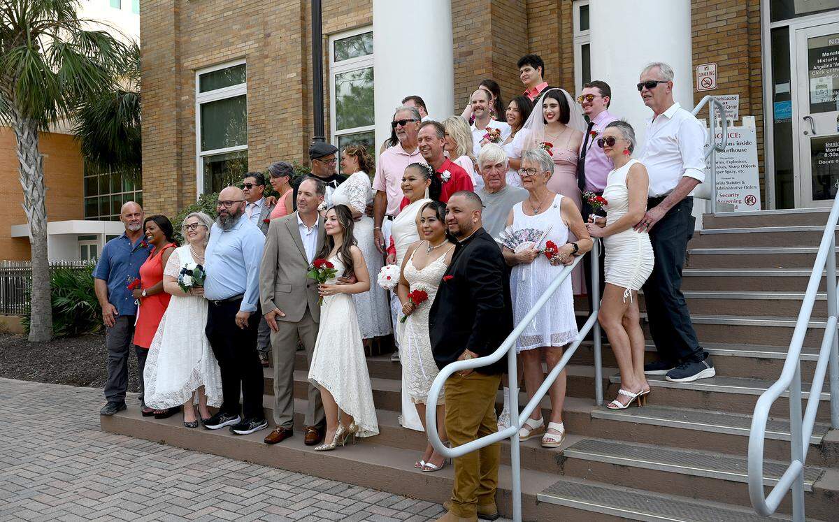 Fourteen couples gathered for a group photo after getting marrien in the Fifth Annual Valentine’s Day Group Wedding in the courtyard of the Manatee County Historical Courthouse on Feb 14, 2025.