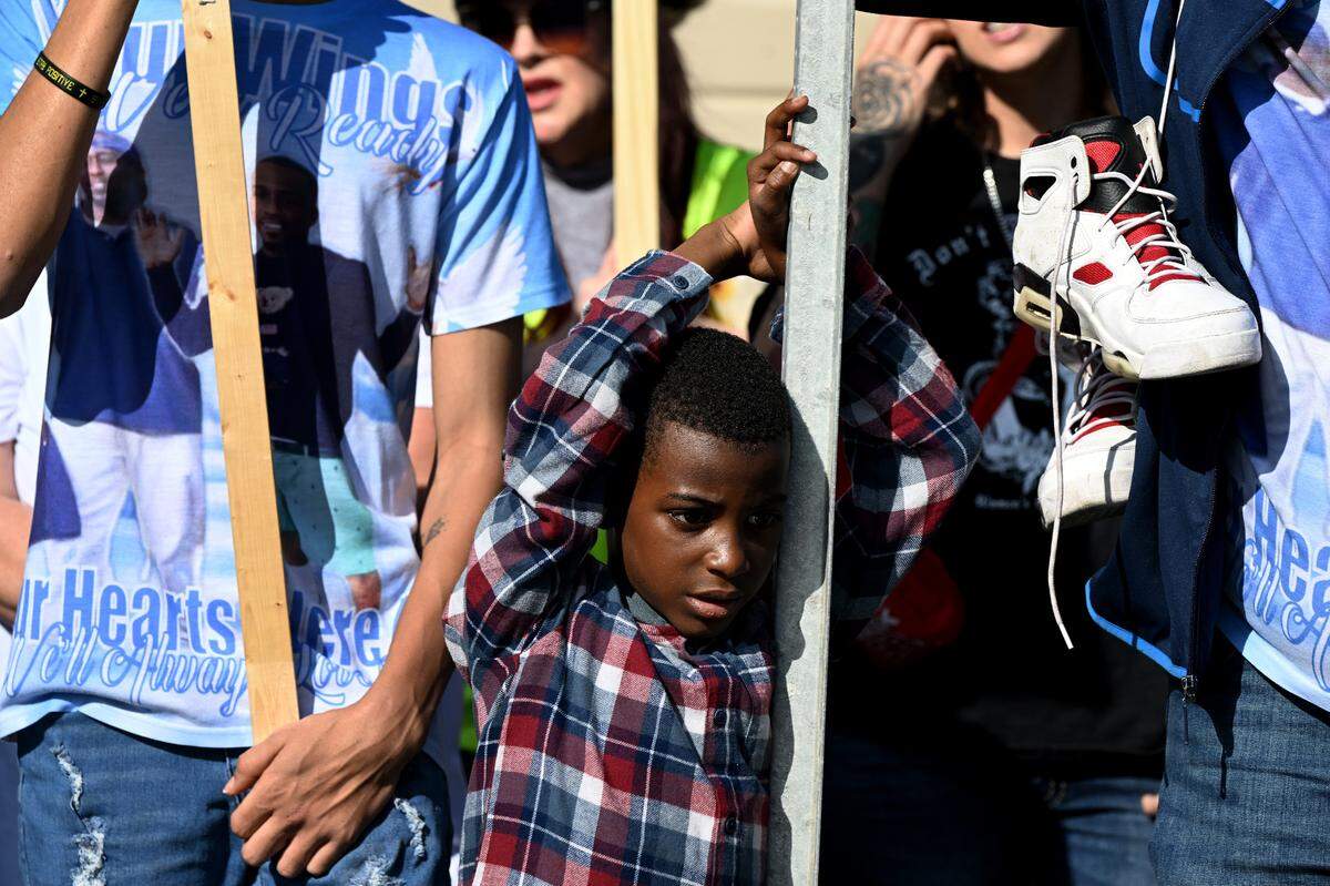 A young boy leans on a sign next to the shoes Breonte Johnson-Davis was wearing when he died. Dozens of protesters gathered at the Palmetto Police Department on Sunday, Jan. 7, 2024, to demand answers following the November death of 36-year-old Johnson-Davis, who died shortly after Palmetto police officers used a stun gun on him, according to a police report.