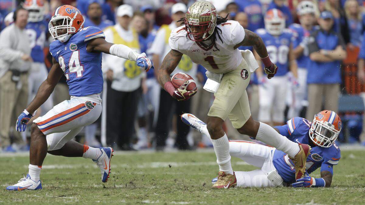 Florida State wide receiver Kelvin Benjamin runs past Florida defensive back Jabari Gorman, right, and defensive back Brian Poole (24) for a 45-yard touchdown on a pass play during the first half of an NCAA college football game in Gainesville, Fla., Saturday, Nov. 30, 2013.(AP Photo/John Raoux)