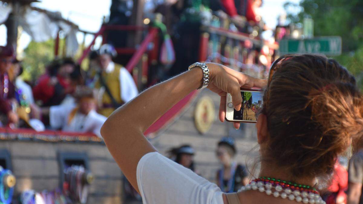 An onlooker snaps a photo of a float at the 80th annual DeSoto Grand Parade on Saturday evening.