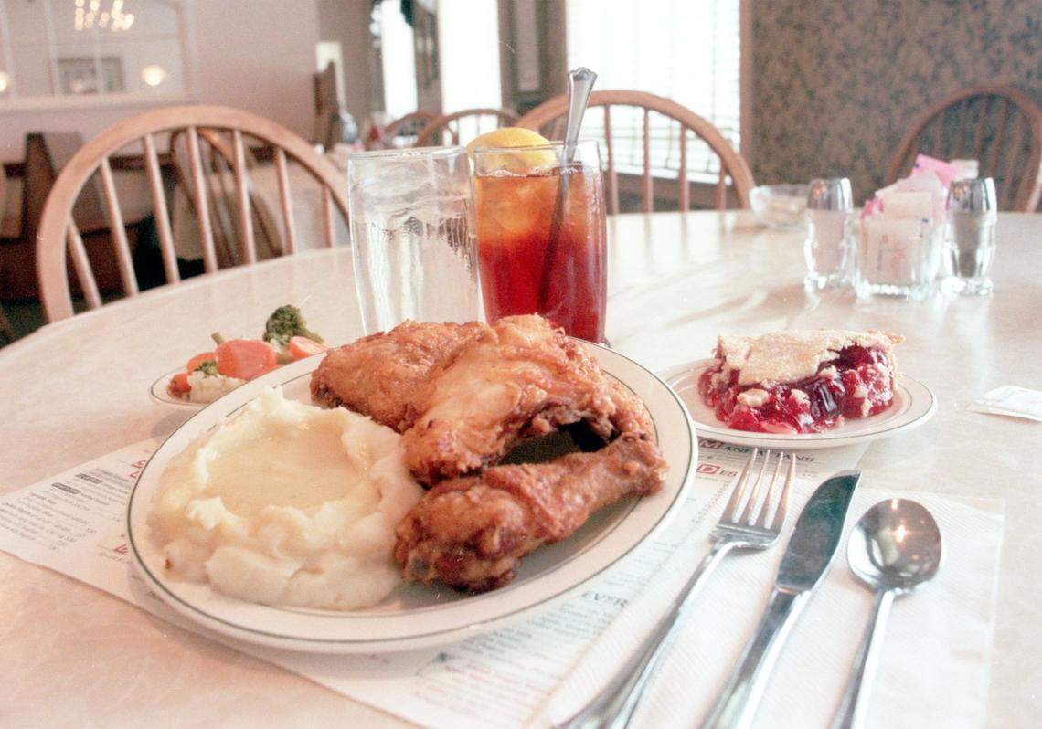 A plate of fried chicken and mashed potatoes on display at Der Dutchman, along with a side of mixed vegetables and cherry pie.