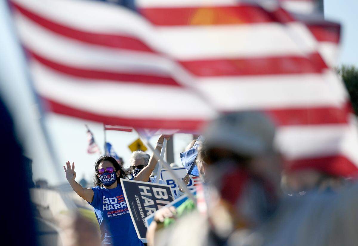 A group of Biden supporters wave flags on the Palmetto side of Green Bridge Monday morning.