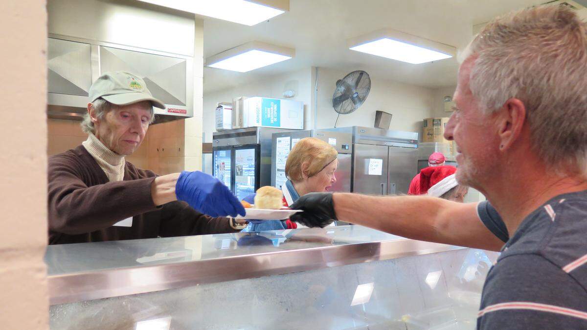 Jim Tinnin, left, handed plates full of hot food to other volunteers at the Salvation Army at the annual Christmas Day meal in 2018. Attendees were seated and served by volunteers, restaurant-style, at the free meal.