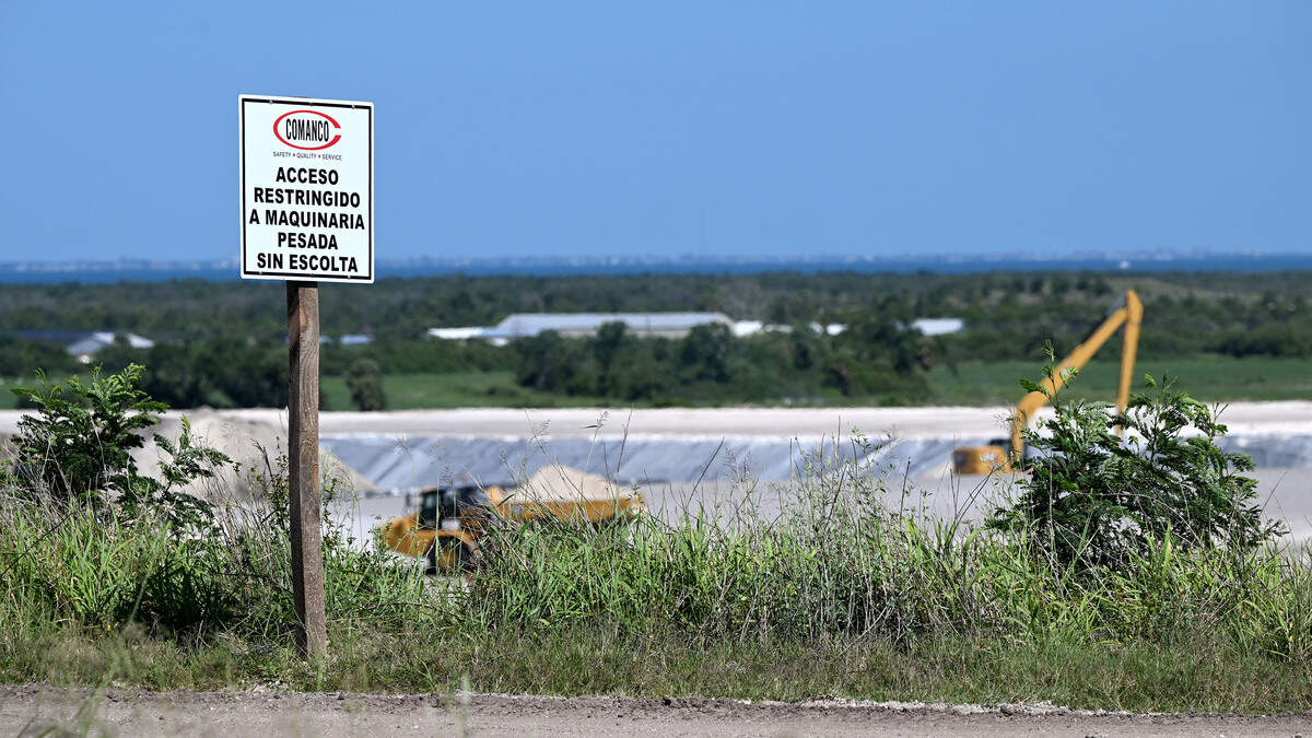 Signs in English and Spanish warn workers that heavy machinery in the area requires an escort as work continues on closing New Gypsum Stack North. Site operators at Piney Point hope to be in the final phase of closing the former phosphate plant, shown on April 15, 2026.