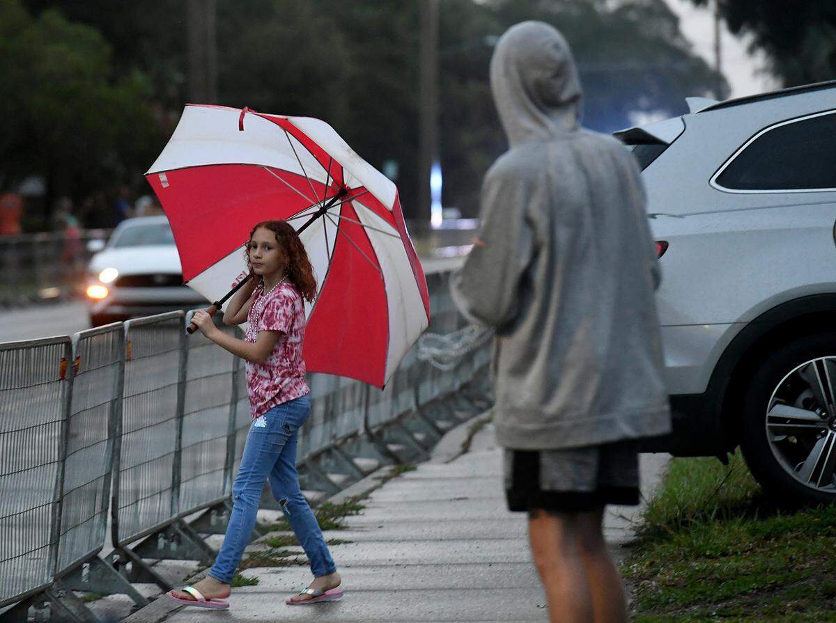 A young girl with a large umbrella looks hopefully at the parade route after the cancellation of the De Soto Parade was announced due to weather.