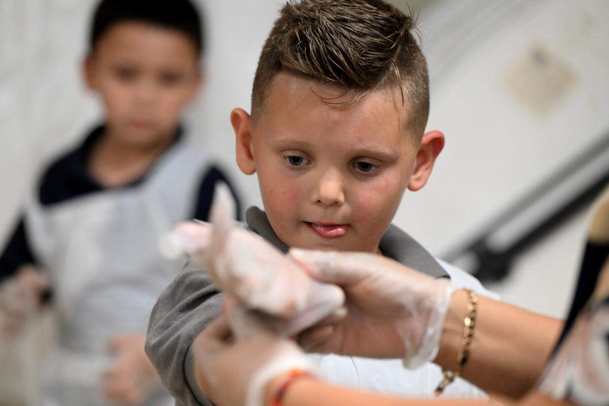 Students put on gloves and aprons to make apple pies for their families’ Thanksgiving celebrations at Visible Men Academy on Friday, Nov. 17, 2023.