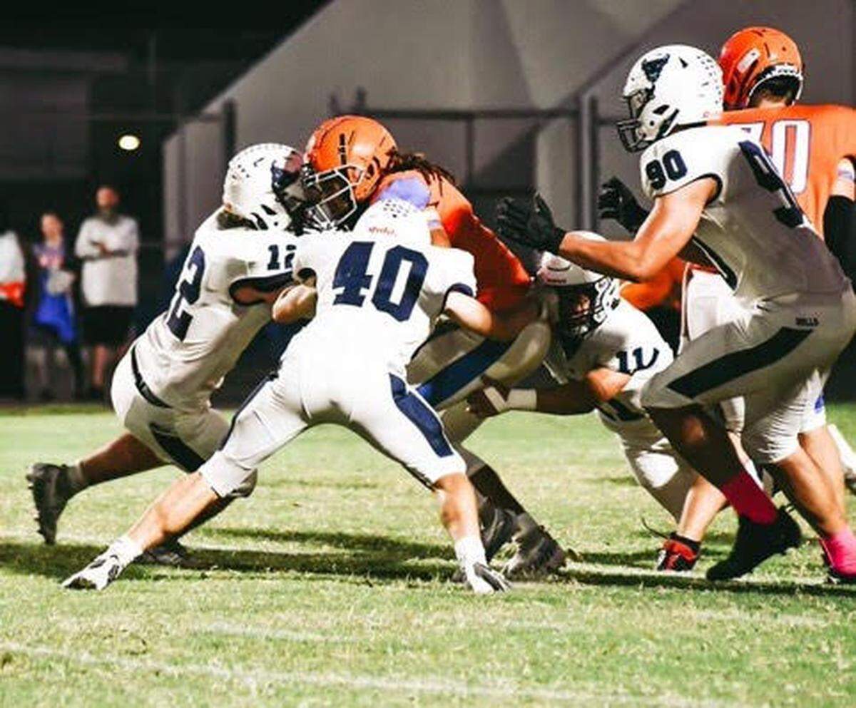 Parrish Community senior linebacker James Keen (No. 40, white uniform) attempts a tackle. He had never played or watched football before joining the new Bulls program four years ago.