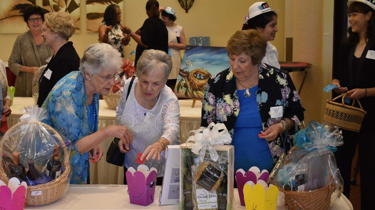 Guests inspect gift baskets that were offered as part of a raffle at the 13th Annual Women of Achievement luncheon Saturday afternoon. The proceeds from the event go toward scholarships for non-traditional students who had their college careers interrupted for various reasons.