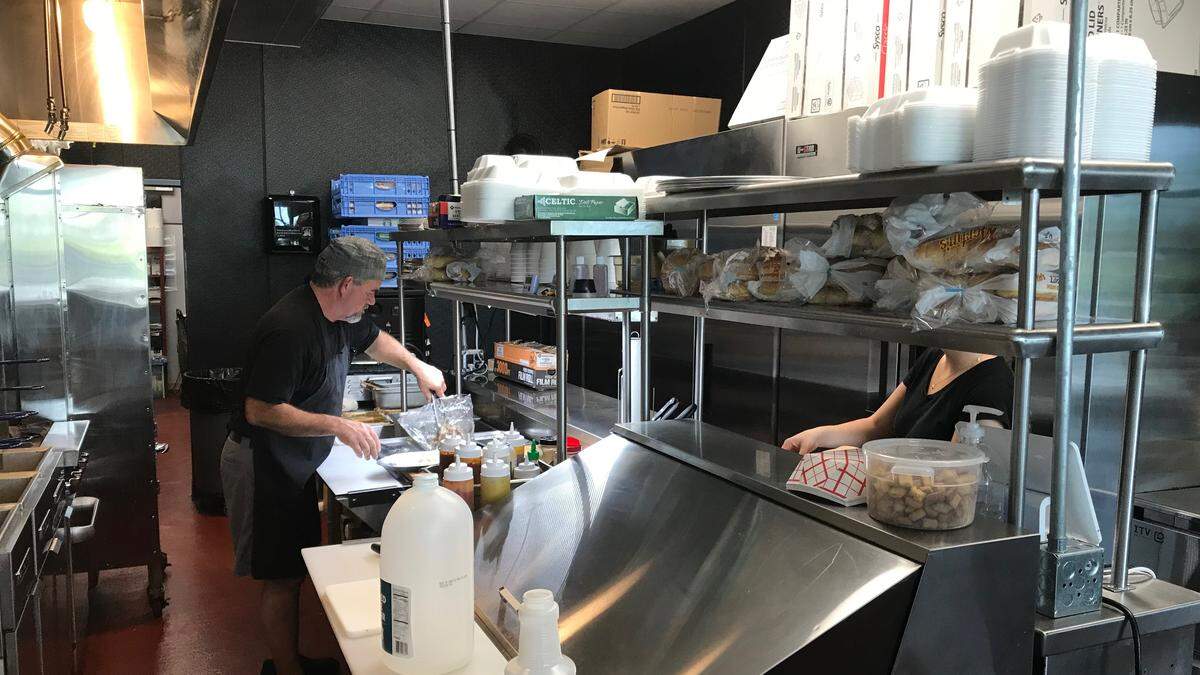 Jimmey Shelton prepares the house special pulled pork platter with black beans and rice at TK Grill & Barbeque.