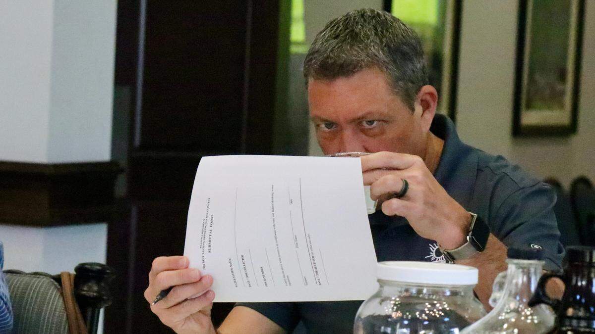 George Kruse checks the color and clarity of a cup of water during an annual drinking water competition March 25, 2022, among six regional water utilities.