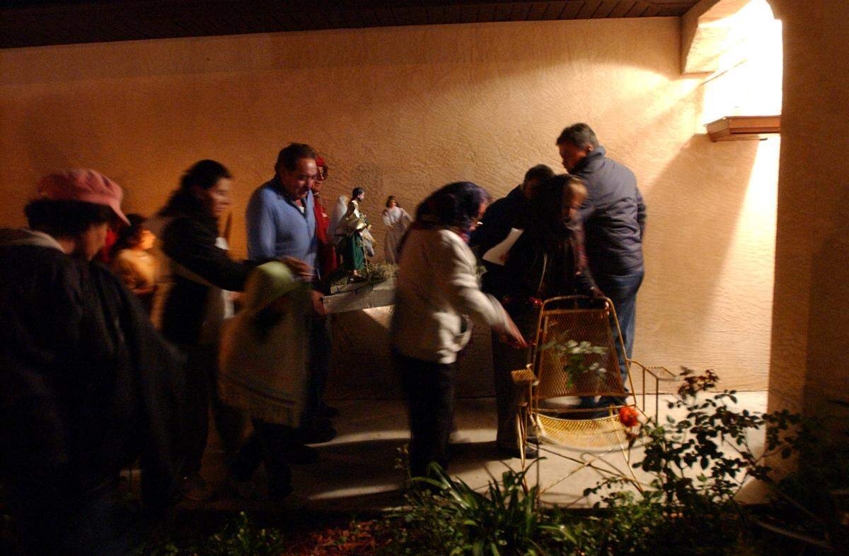 12/22/2005--Participants sing and pray as they carry candles and statues of Joseph and Mary from house to house during a La Posada celebration in Palmetto.