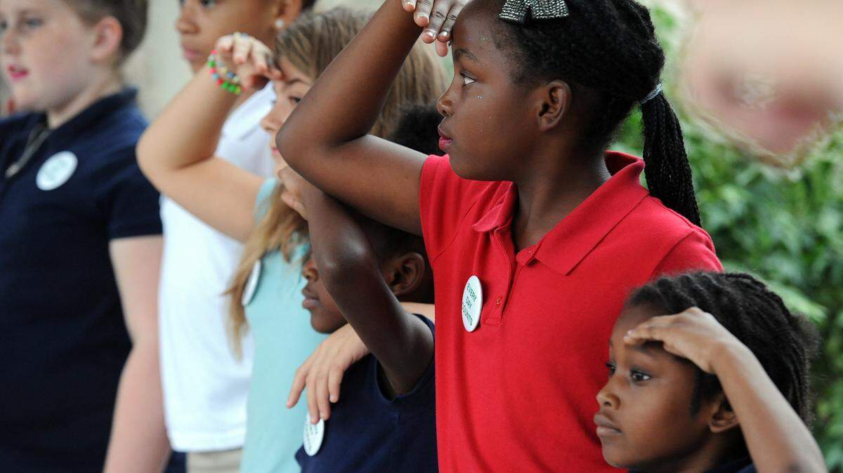Oneco Elementary students salute as a bus from Bay Pines brings veterans to the school to be served a meal from the students and a handmade lap blanket.