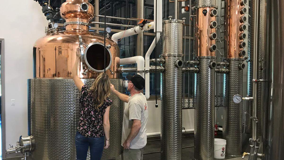 Michelle Russell and Steve Milligan stand among gleaming new equipment at Loaded Cannon Distillery and Tasting Room.