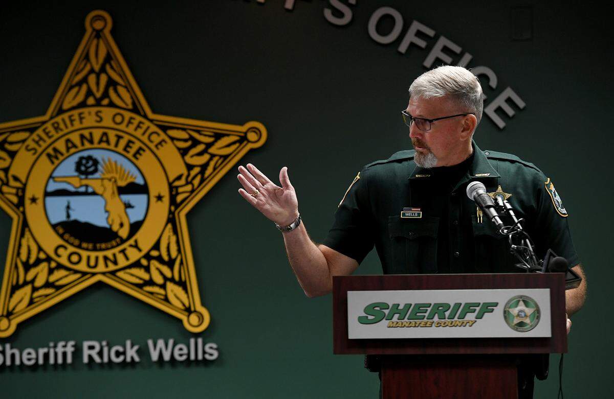 Manatee County Sheriff Rick Wells gestures to large mug shots to his side during a press conference at the District 3 office in Bradenton on Jan. 28, 2022. He detailed the arrest of a food service worker at the jail who was smuggling drugs into the facility. Other inmates are facing charges related to the drug scheme.