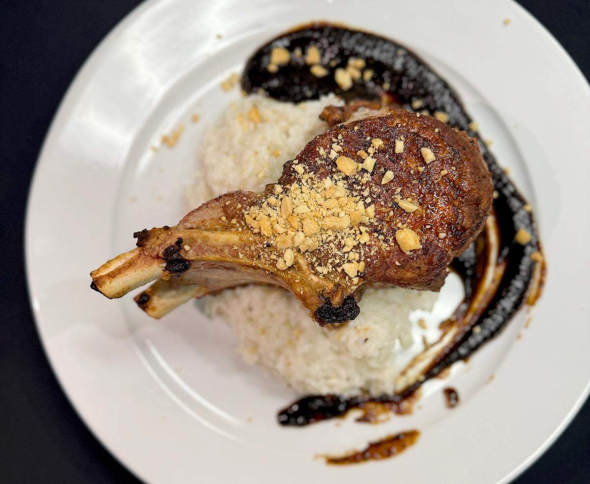 The double cut pork chop is served over house-made coconut rice and Korean bbq sauce garnished with peanuts at Sofra Kitchen Bar & Bistro in downtown Bradenton.