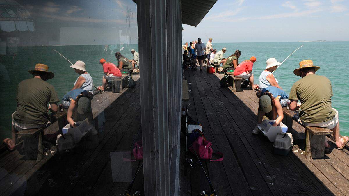 People are reflected in the windows of the Anna Maria City Pier as they enjoy the day fishing in this 2014 file photograph. 
 File Photo-GRANT JEFFERIES/Brdenton Herald