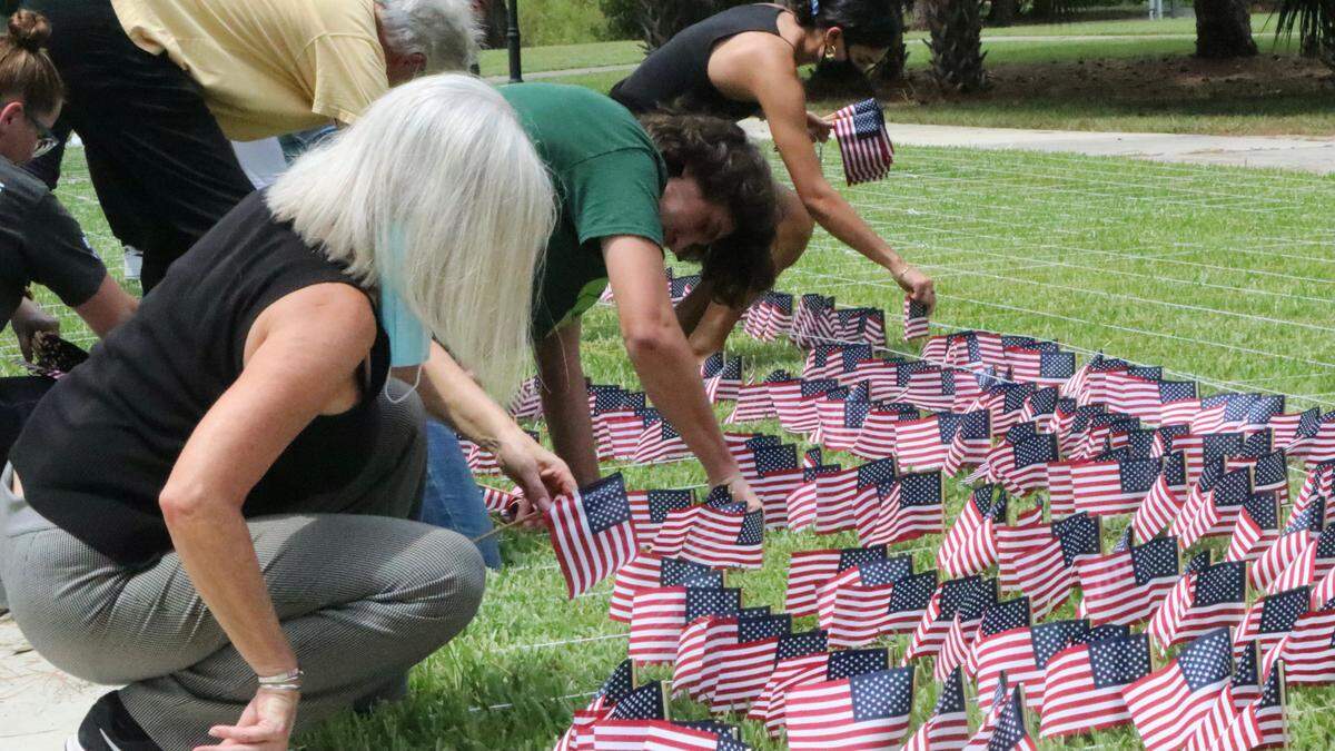 9/6/2021--Volunteers plant flags at USF Sarasota-Manatee in honor of the 2,977 victims who died in the terrorist attacks of Sept. 11, 2001. Shown above are Carolyn Dysen, foreground, and Evan Fruehauf in green shirt.