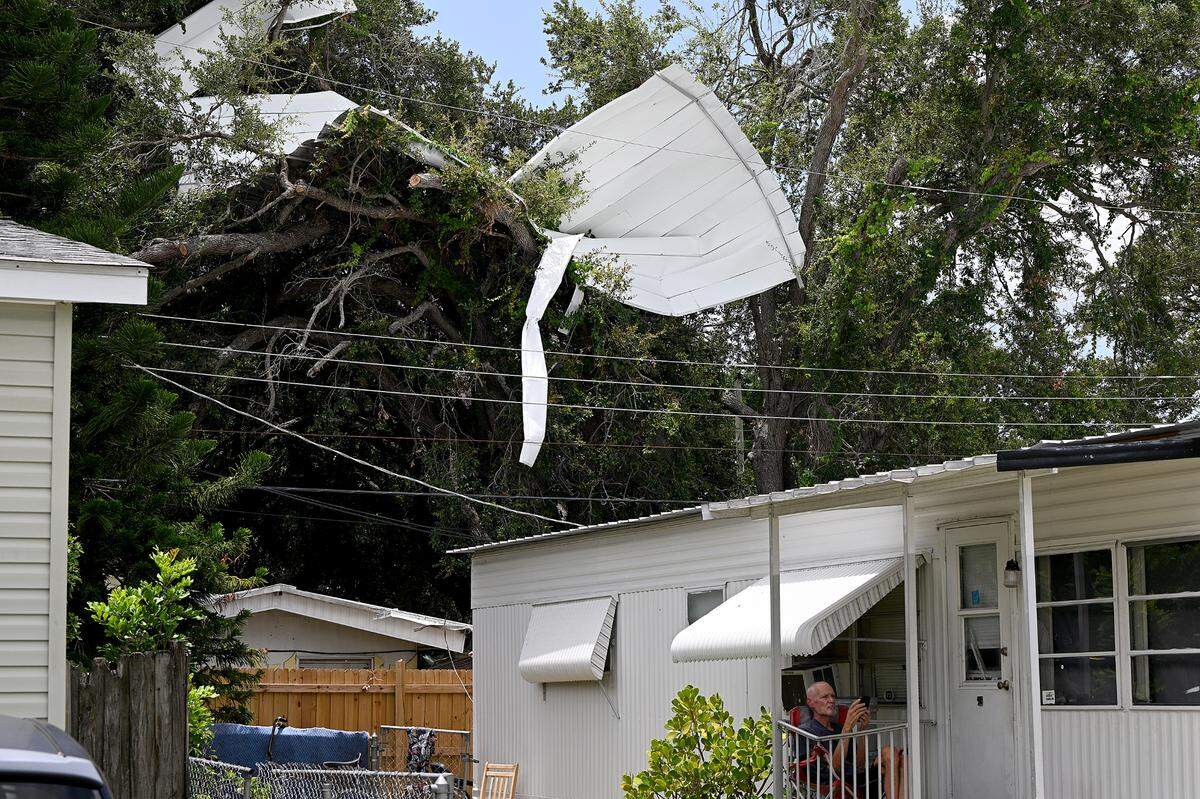 An aluminum roof remains perched in some trees after Hurricane Ian in Pic Town Estates Mobile Home Park where some residents are worried about the level of violence and danger in their neighborhood following three homicides in the past month.