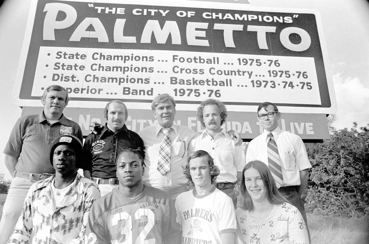 "The city of champions" Palmetto sign to honor the championship teams and band from Palmetto High School.  Standing are, "Butch" Hughes, the basketball coach, Frank Turner, the football coach, Mayor John J. "Toby" Holland, Pat Palmer, the track coach, and David Brown, the band director.  In front are Wilmer Fowler, a basketball player, James "Mike" Simms, a basketball and football player, David Foy, a track athlete, and Susan Davis, a member of the band.