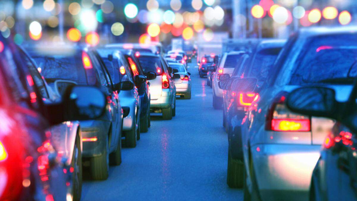Driving a car in a a city with a traffic jam at night, proceeding slow in a line of cars with red tail lights during the rush hour. view from inside the car. Blurred streets lights on the background. Dusk, blue skylight.