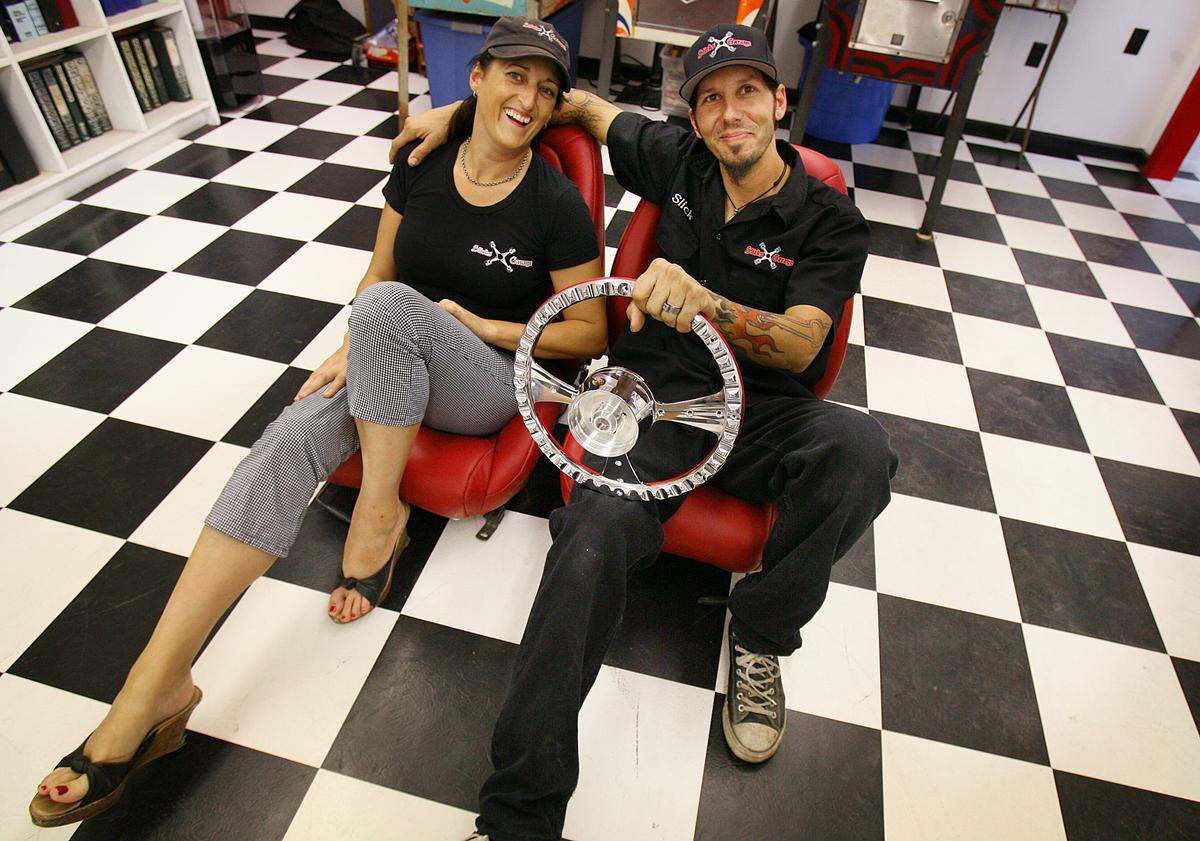 Jane Hunter and Slick of Slick’s Garage sit on the custom redesigned recycled seats and hold the steering wheel in this file photo.