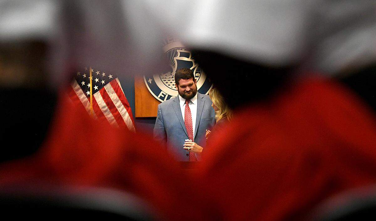 08/24/21—County Commissioner James Satcher seen through the red robes of Women’s Voices of SW Florida who dressed as Handmaids to attend the meeting.
