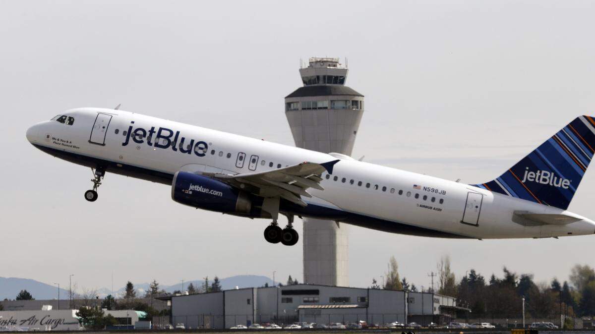 FILE - In this April 23, 2013, file photo, a JetBlue plane takes off in view of the air traffic control tower at Seattle-Tacoma International Airport, in Seattle. Alaska Airlines and JetBlue Airways still rank highest in the annual J.D. Power survey of passengers on the nine largest North American airlines, and the firm says overall traveler satisfaction with the industry is at a 10-year high. J.D. Power said Wednesday, May 11, 2016, that Alaska ranked highest among traditional airlines for the ninth straight year and JetBlue was the top-rated low-cost carrier for the 11th year in a row. (AP Photo/Elaine Thompson, File)