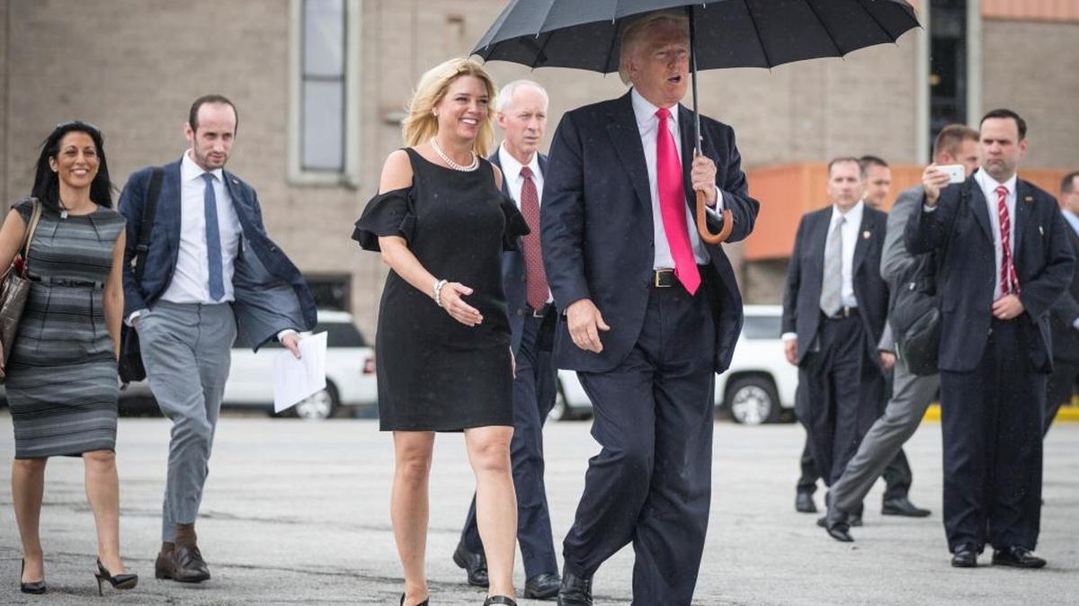 Republican presidential candidate Donald Trump walks in the rain with Florida Attorney General Pam Bondi, as they arrive at a campaign rally in Tampa, Wednesday, Aug. 24, 2016.