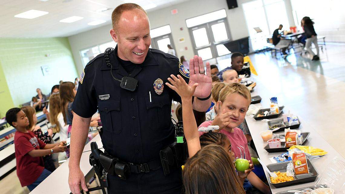 Bradenton Police officer Rusty Ackerman gives high fives to students at lunch as he fills in as a school resource officer at Miller Elementary School. The Manatee County School District wants municipalities to help fund a state mandate to have armed officers in every school. Manatee County rejected the proposal, now being debated by Palmetto and Bradenton.