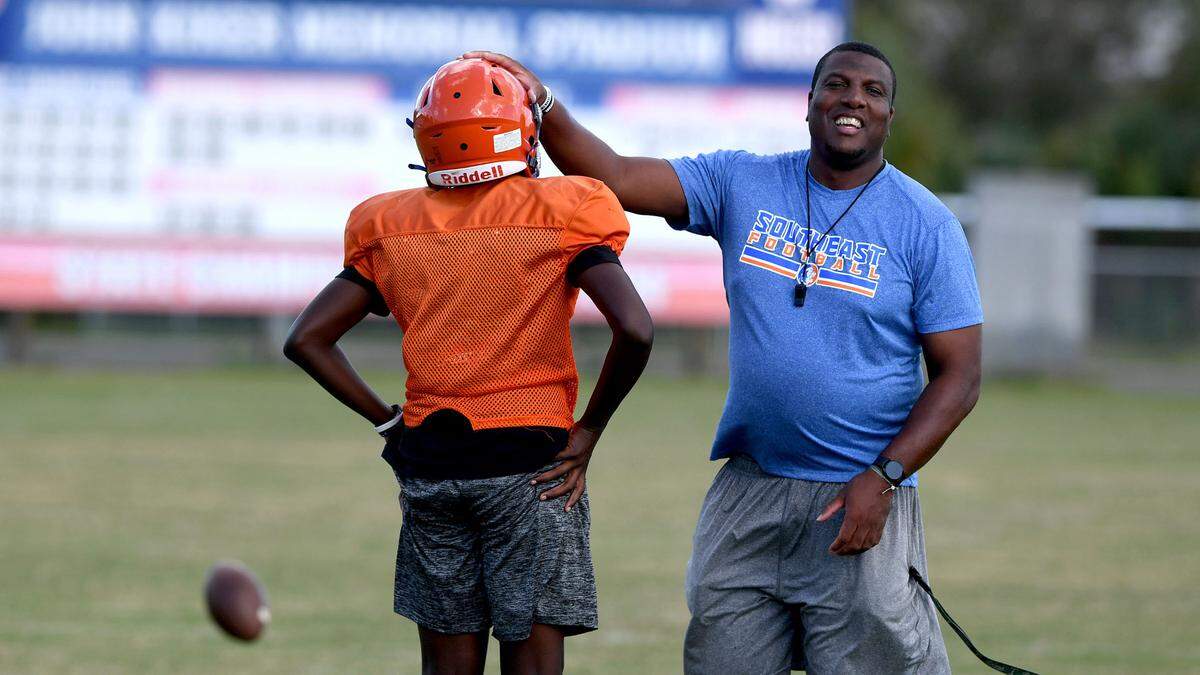 Head coach Brett Timmons laughs with one of the players during a drill at Southeast High School football practice, October 24, 2022.