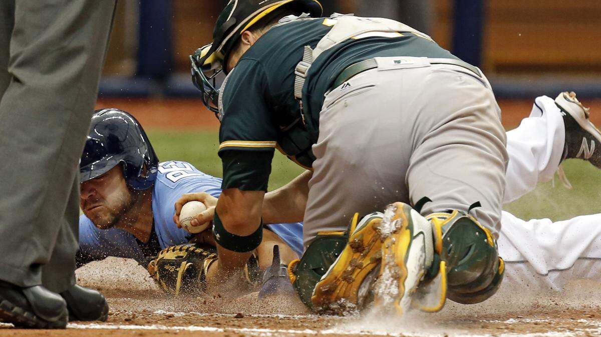 Tampa Bay Rays' Steve Pearce slides in safely to score on a sacrifice fly by Brandon Guyer ahead of a tag by Oakland Athletics catcher Stephen Vogt during the fourth inning of a baseball game, Sunday, May 15, 2016, in St. Petersburg, Fla. (AP Photo/Mike Carlson)