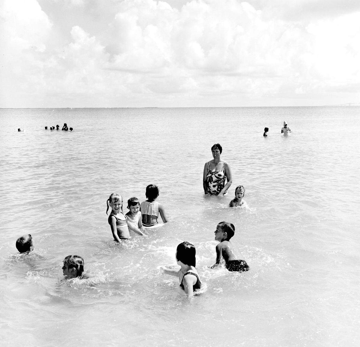 Multiple children playing and swimming at the Manatee Public Beach.
