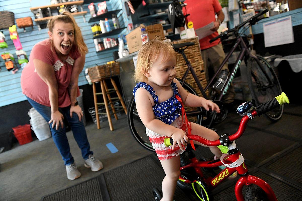 Megan Giammatteo laughs as Natalie, 2, gets on her first bike at Ringling Bicycles. Dave and Julie Holt have owned Ringling Bicycles for 27 or 28 years--they’re not sure--but they are closing shop in June.