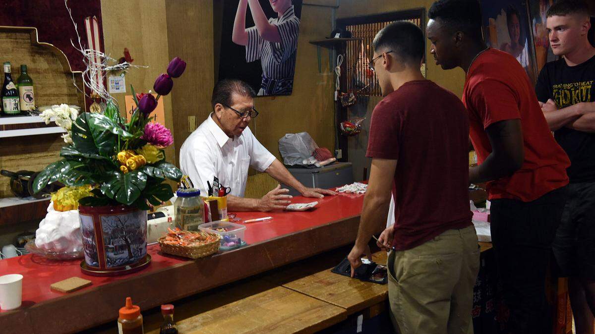 Yoshimasa Shiroma, 85, talks to Marines from Camp Schwab as they settle their bill at Ocean Sushi Restaurant in Henoko, a village known to be friendly to Americans in Okinawa, Japan, on July 26, 2015. Shiroma has been in business in Henoko for 42 years, mostly serving the military from neighboring Camp Schwab. (Tiffany Tompkins-Condie/McClatchy DC/TNS)