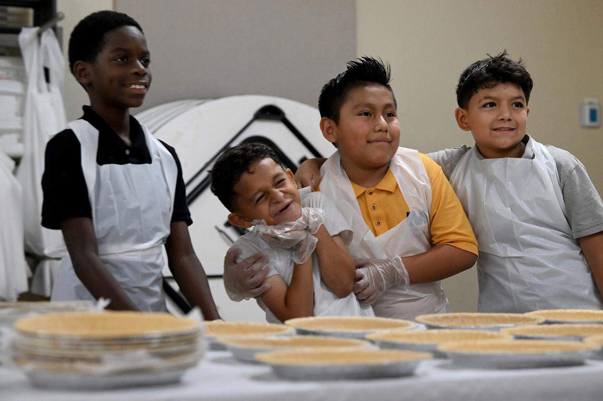 Students mug for a photo while they make apple pies for their families’ Thanksgiving celebrations at Visible Men Academy on Friday, Nov. 17, 2023.