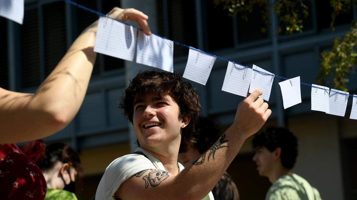 A New College student reads notes written by students stating why they love their school in front of the Cook Library as students participated in a one-hour walkout to protest DeSantis’ recent education-related policies.