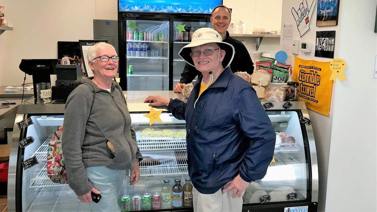 John Mahoney, behind the counter, who owns Bridge Street Deli, 119 Bridge Street, Bradenton Beach, with his wife, Mary Maloney, greets customers John and Dot Fleming.