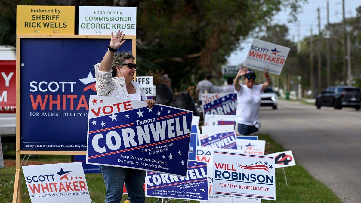 Tamara Cornwell and other locals hold signs outside the Church of Hope in Palmetto on Nov. 5, 2024.